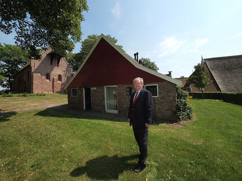 Wil van den Berg op het “dorpsplein” van Jannum. Links het kerkje van Jannum, achter hem één van de vier terplogementen.