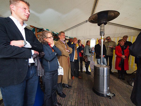 Rondom het hellevuur. Rechts, in een rode mantel, een bedenkelijk kijkende gedeputeerde Jannewietske de Vries. Derde van links Jack van den Berg van de Marrekrite.