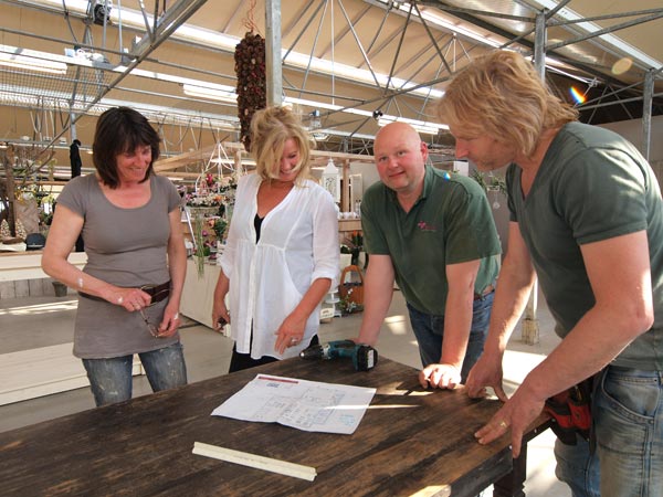Froukje van de Bunt, Anita, Jeroen en Thomas Maarsen bestuderen een bouwtekening van de immense bloemenzaak.
