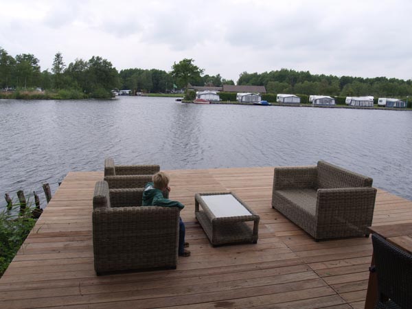 Zicht op camping De Kluft vanaf het terras van een Weerribben Lodge.