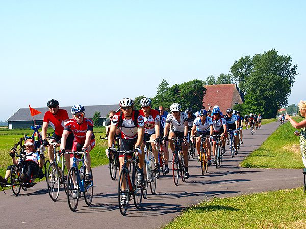 Dik 14.000 fietsers reden in colonnes en in een flink tempo op één dag de Elfstedenroute, hier op het traject Sneek-Woudsend. Veel snelle fietsers droegen een helm en dat bleek, gezien de goede afloop van enkele valpartijen, geen overbodige persoonlijke bescherming.