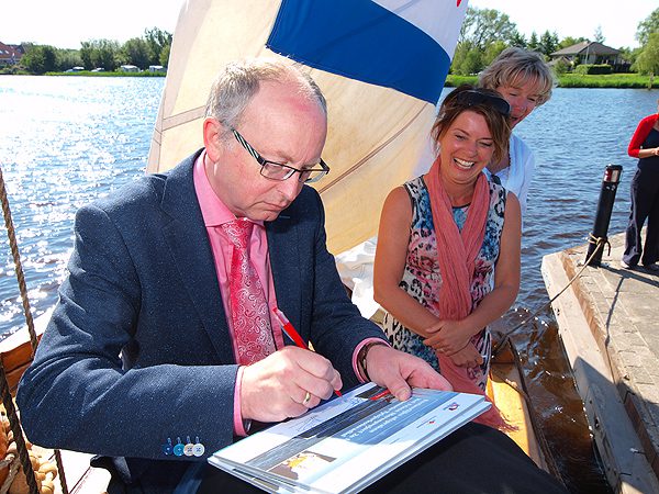 Wethouder Schippers, gedeputeerde De Vries en burgemeester Waanders (v.l.n.r.) ondertekenen hun afspraken op de rug van één van de schippers van het houten skûtsje Aebelina van het plaatselijke skûtsjemuseum.
