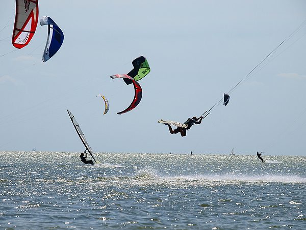 Schermen van kitesurfers vullen de weiden en de hemel bij Mirns.